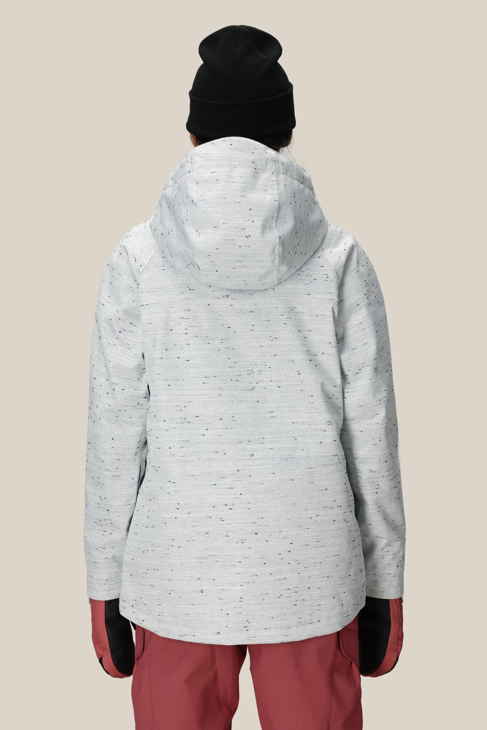 A person is shown from the back against a plain beige background, wearing the 686 Women’s Athena™ Insulated Jacket in light gray, paired with red pants, black gloves, and a black beanie.