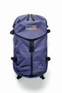 A purple 686 Mystery Ranch x 686 Qi 22L Snow Pack with black straps and zippers is displayed on a white background. The front features the Mystery Ranch logo and an orange 40 label, making it perfect for versatile use as a gym or snow bag.