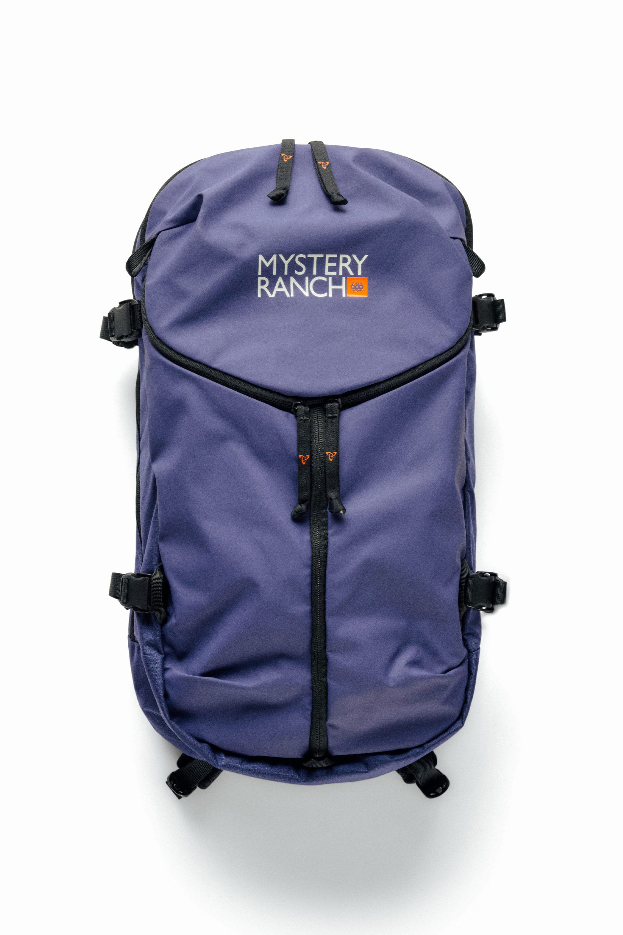 A purple 686 Mystery Ranch x 686 Qi 22L Snow Pack with black straps and zippers is displayed on a white background. The front features the Mystery Ranch logo and an orange 40 label, making it perfect for versatile use as a gym or snow bag.