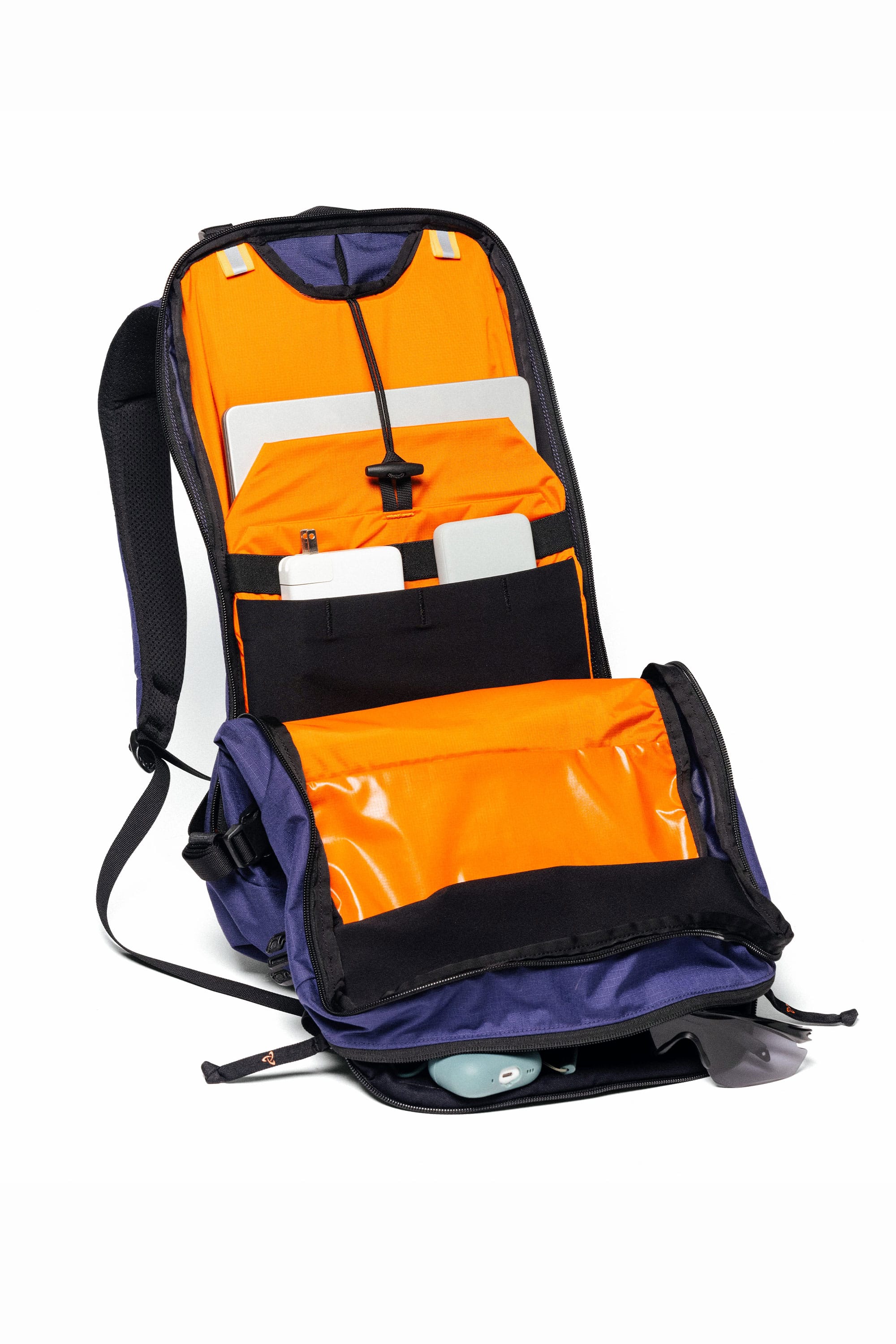 The 686 Mystery Ranch x 686 Qi 22L Snow Pack features a bright orange interior with organized compartments for a laptop, tablet, pens, accessories, and a lower pocket perfect for sunglasses.