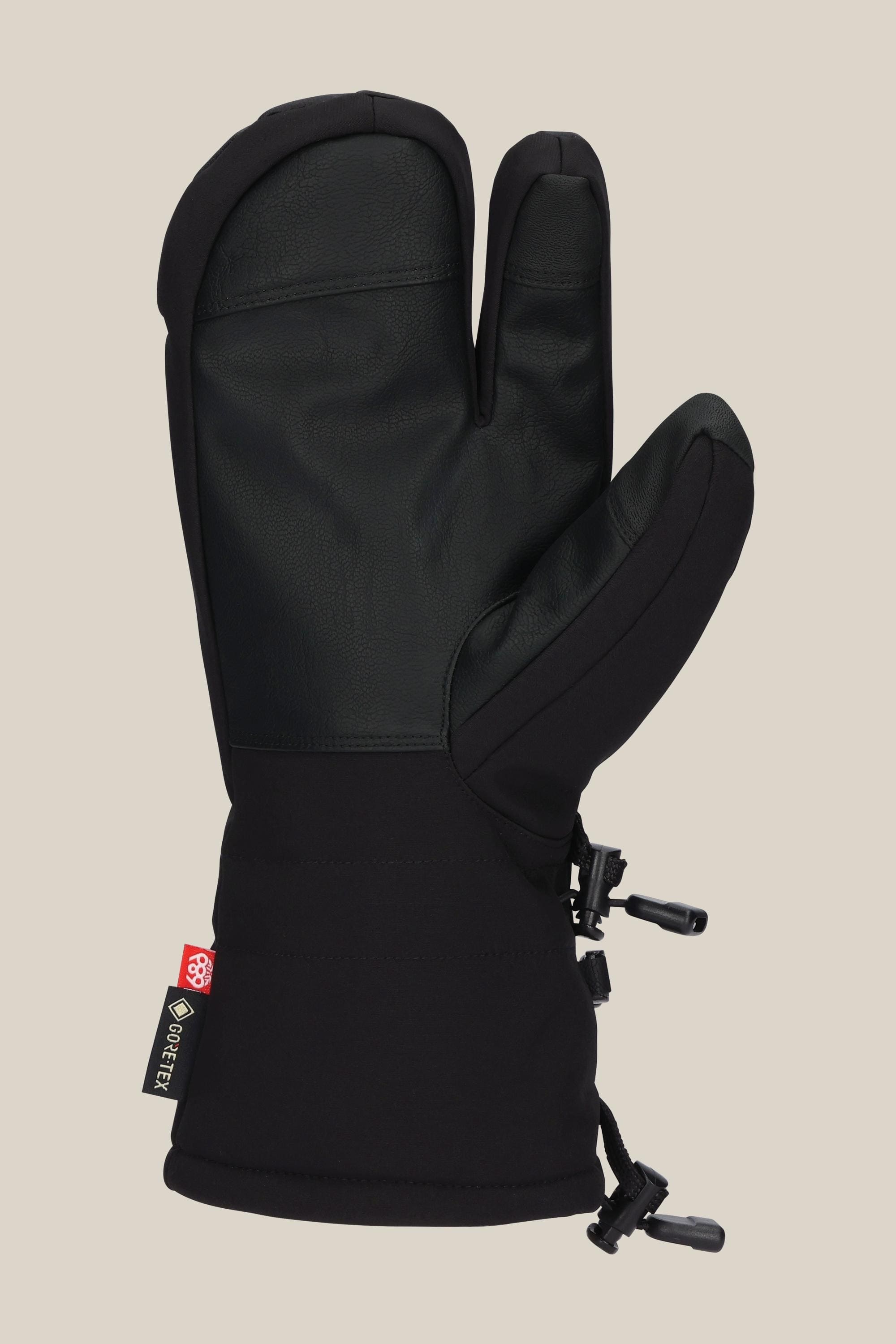 The 686 Men's GORE-TEX Linear Trigger Mitt by 686 is a black three-finger winter glove with a textured palm, adjustable wrist strap, and GORE-TEX tag, shown against a plain beige background.