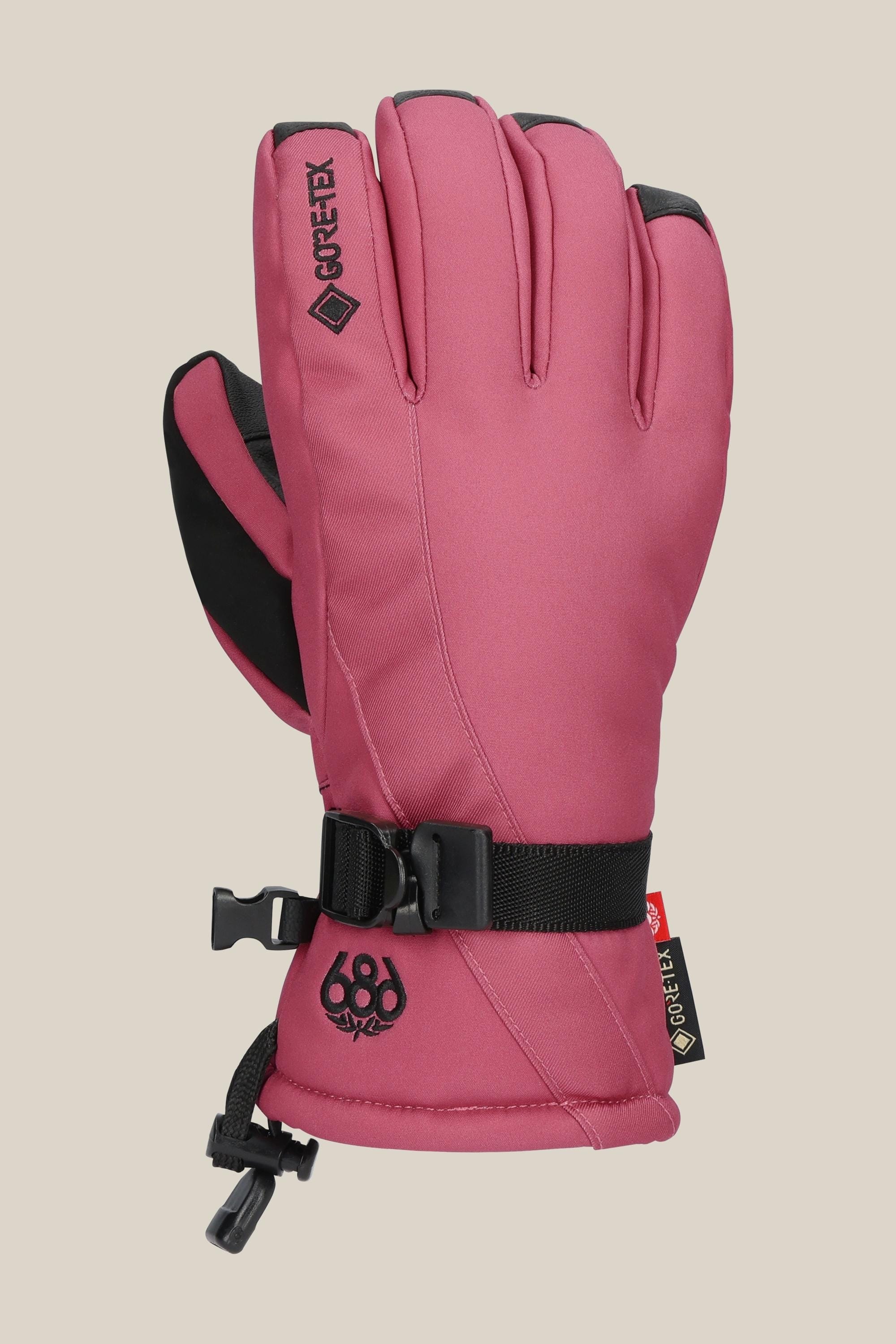 The 686 Womens GORE-TEX Linear Glove features a pink insulated design with black accents, an adjustable strap, GORE-TEX label, and the 686 logo by the wrist, shown against a beige background.