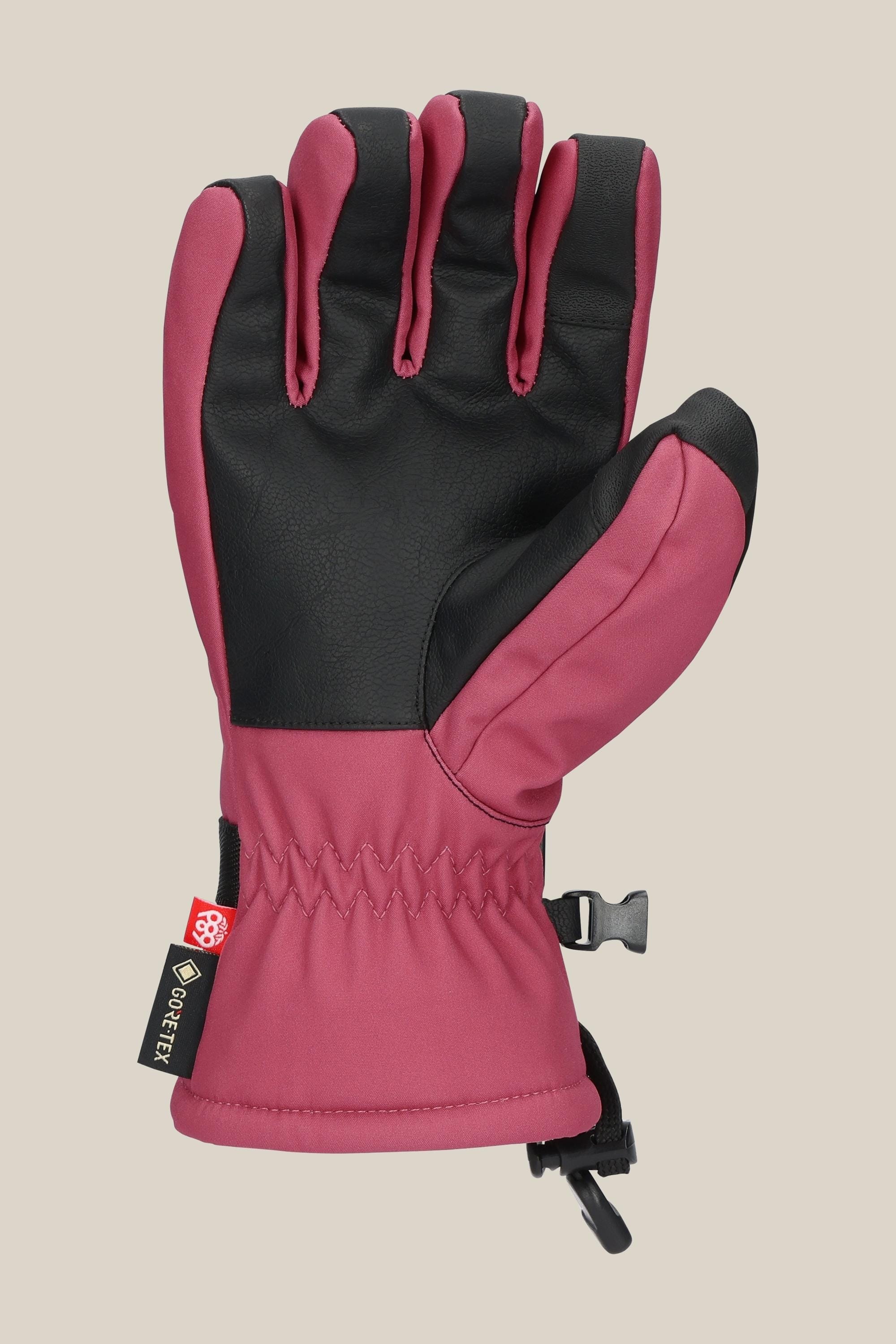 A single 686 Womens GORE-TEX Linear Glove in pink with black palm, wrist elastic, adjustable strap, and clip is shown against a beige background. This PU glove by 686 ensures stylish winter protection for women.
