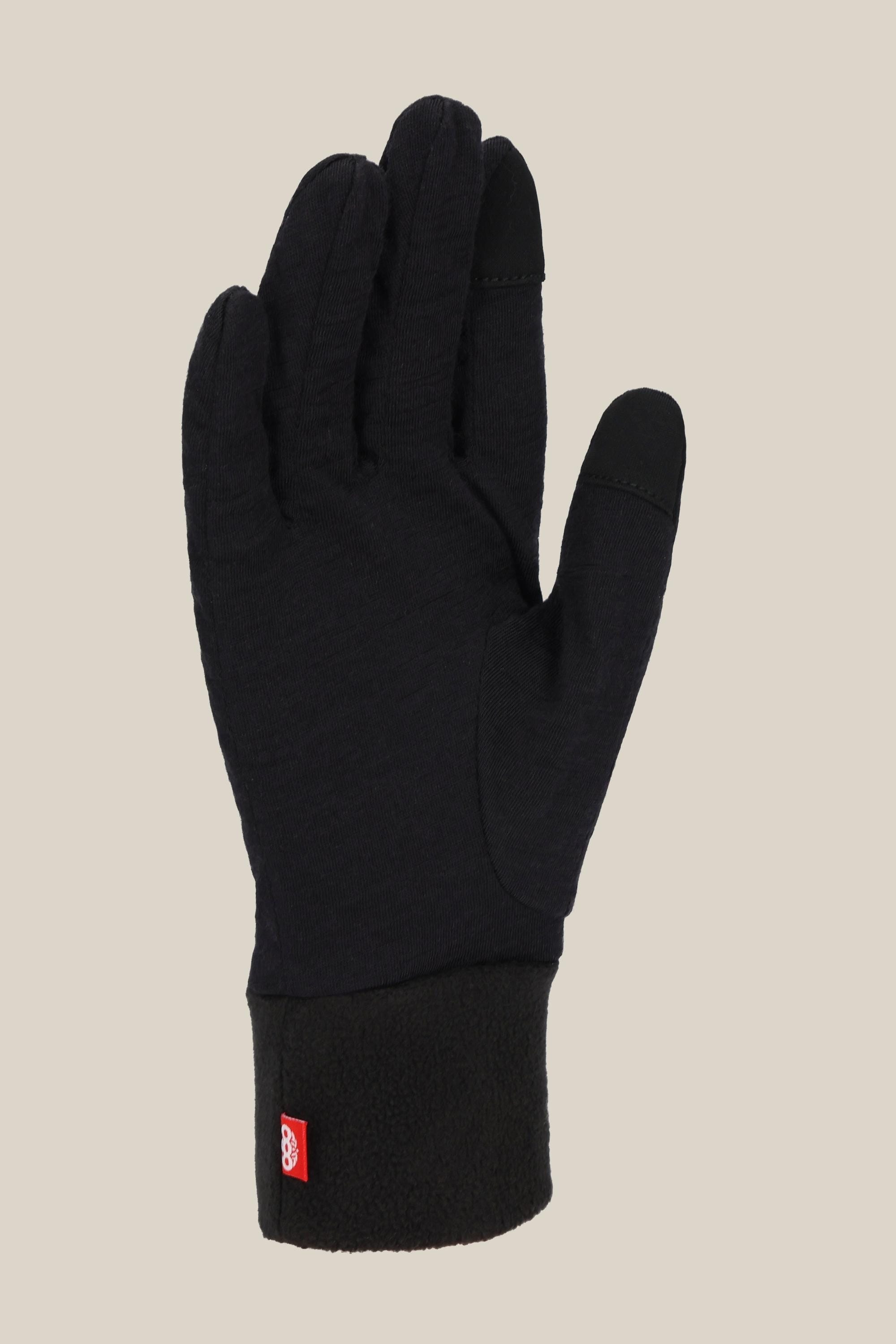 The 686 Womens Merino Glove Liner by 686, made from soft polyester-merino fabric with a fleece cuff and small red tag near the wrist, is shown palm up against a beige background.