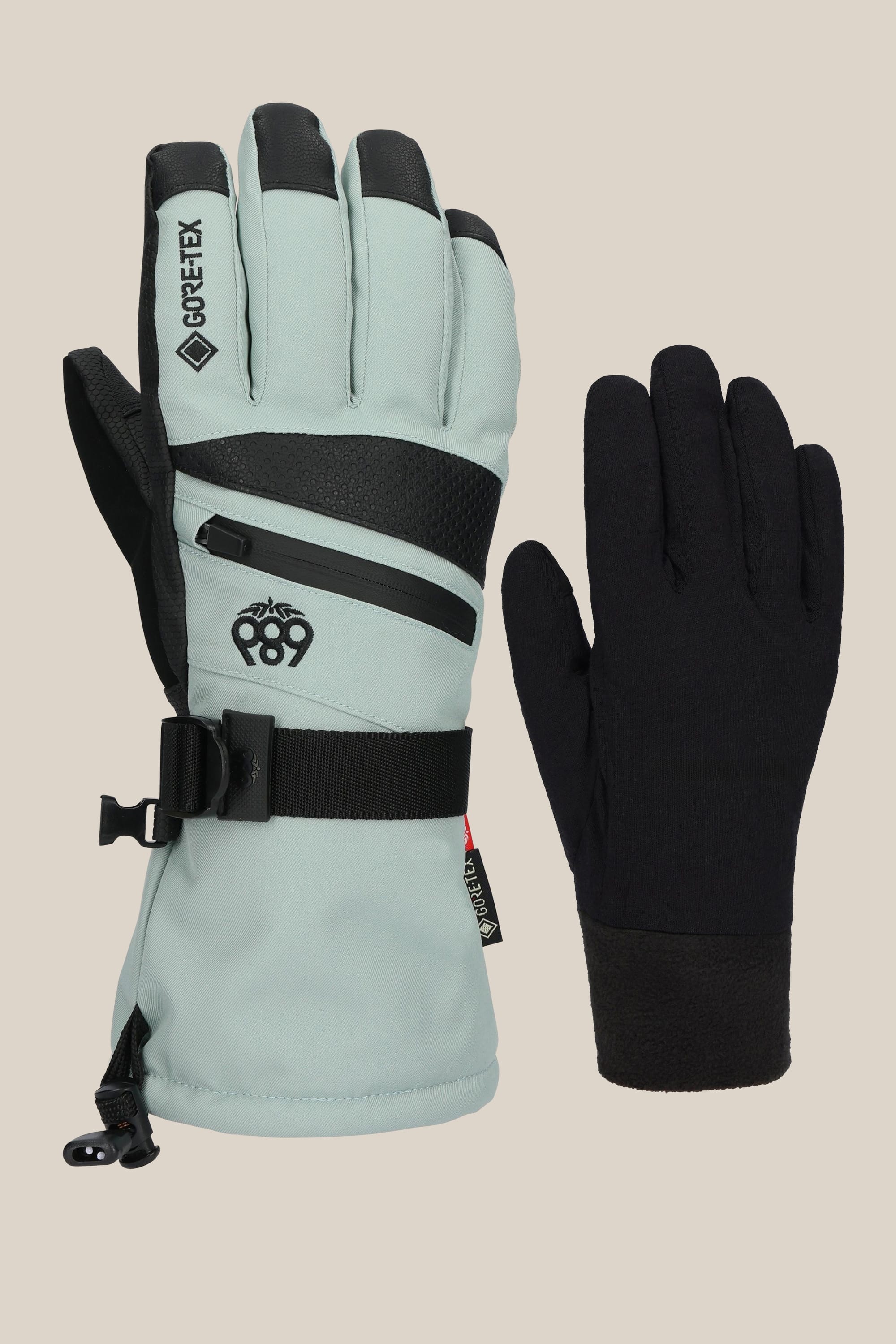 The 686 Womens GORE-TEX Smarty 3-In-1 Gauntlet Glove by 686 features one light gray PU glove with black accents, zippers, and a wrist strap alongside a plain black glove, both displayed side by side against a neutral background.