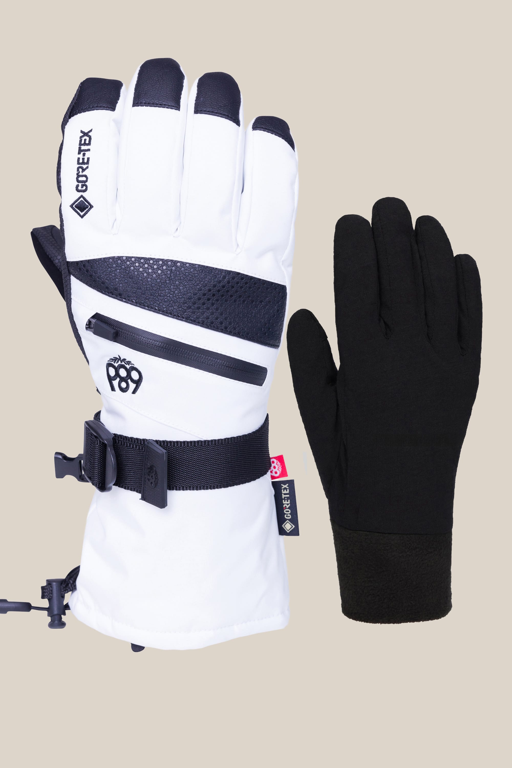 The 686 Womens GORE-TEX Smarty 3-In-1 Gauntlet Glove, featuring white and black design with a zipper, strap, and GORE-TEX branding, is shown next to a simple black poly glove on a light beige background.