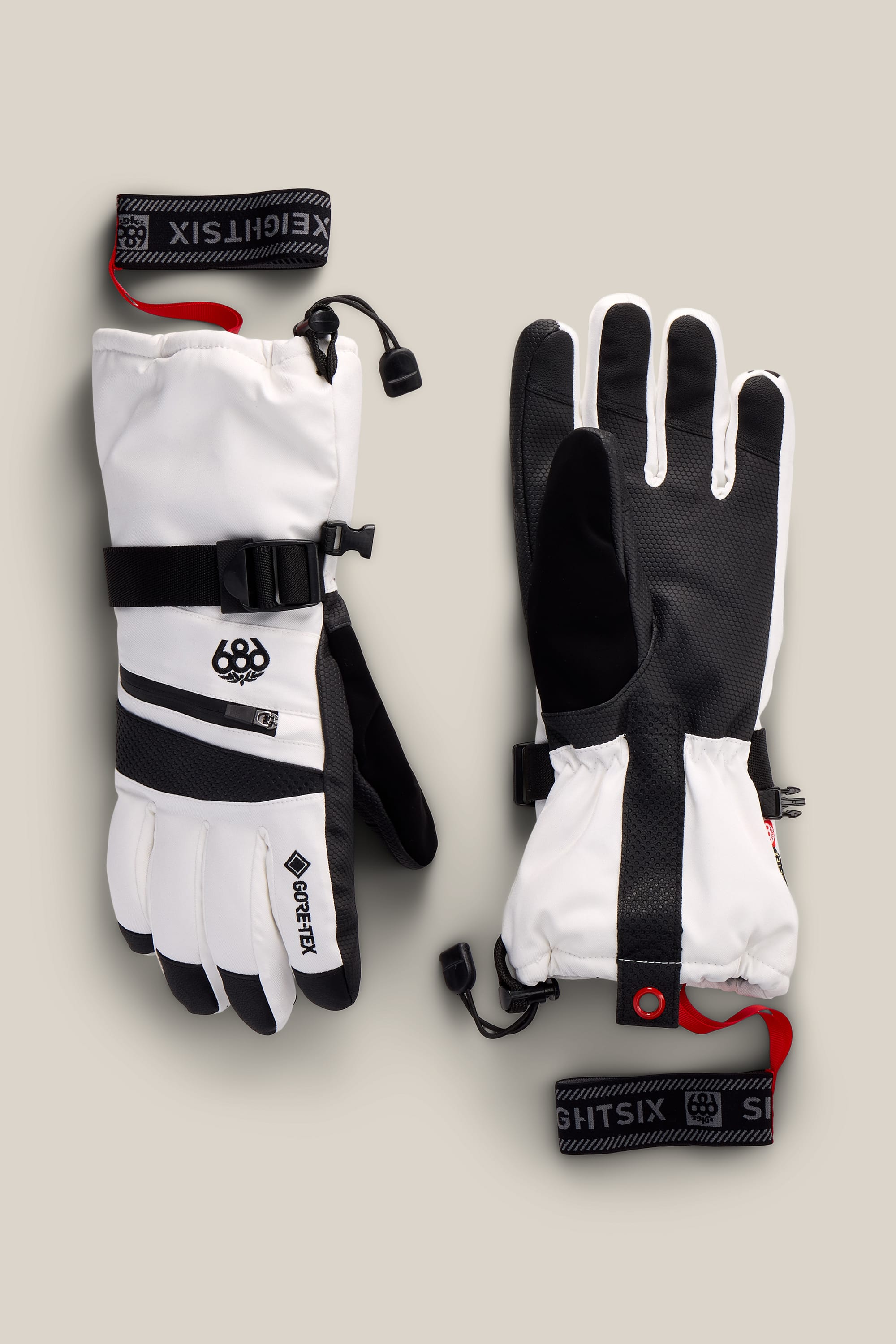 A pair of 686 Women’s GORE-TEX® SMARTY® 3-In-1 Gauntlet Gloves in white and black, featuring insulated construction, adjustable wrist straps, and signature branding details, displayed on a neutral background.