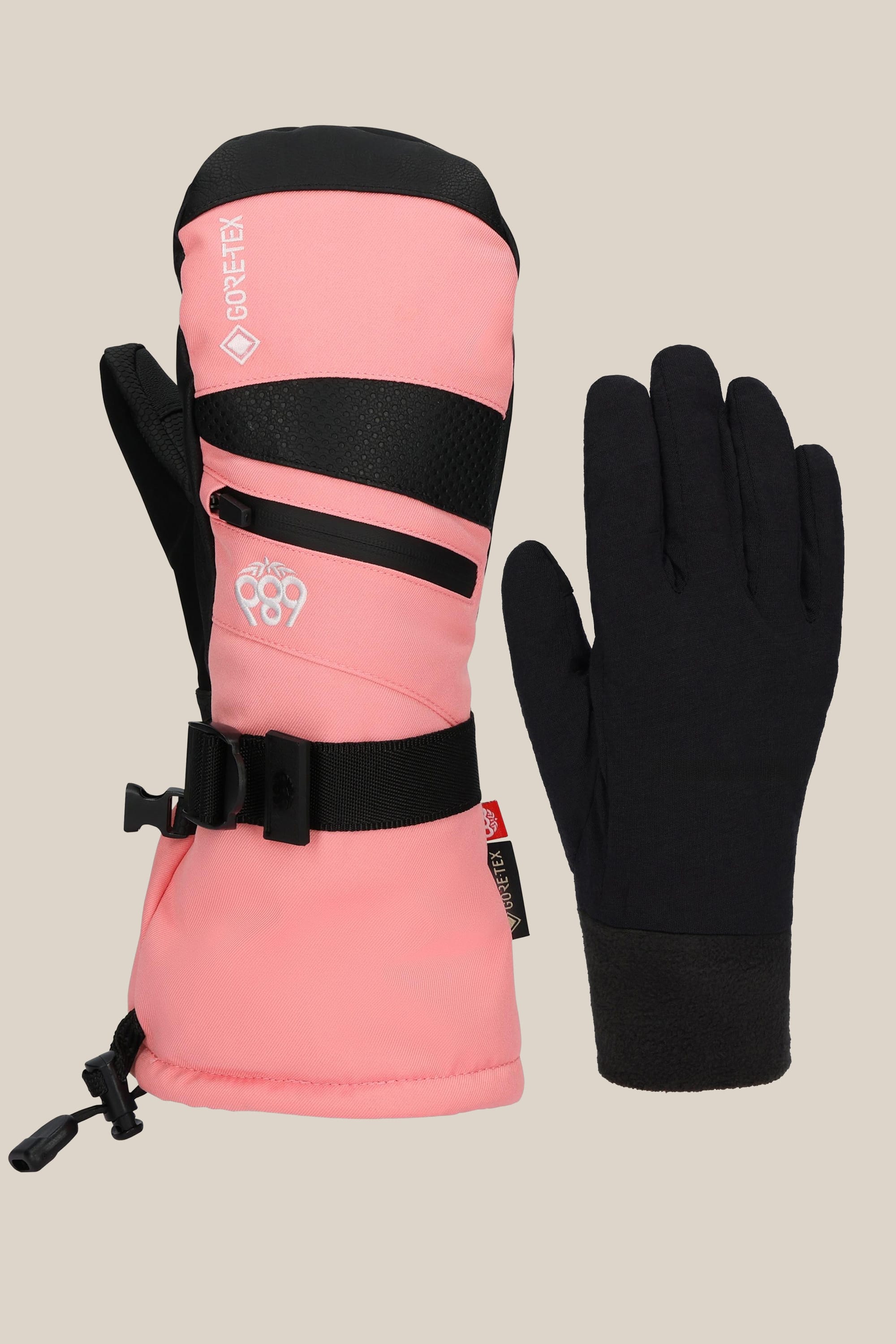 The 686 Womens GORE-TEX Smarty 3-In-1 Gauntlet Mitt in pink and black, featuring adjustable straps, is shown beside a plain black glove liner by 686, both set against a beige background.