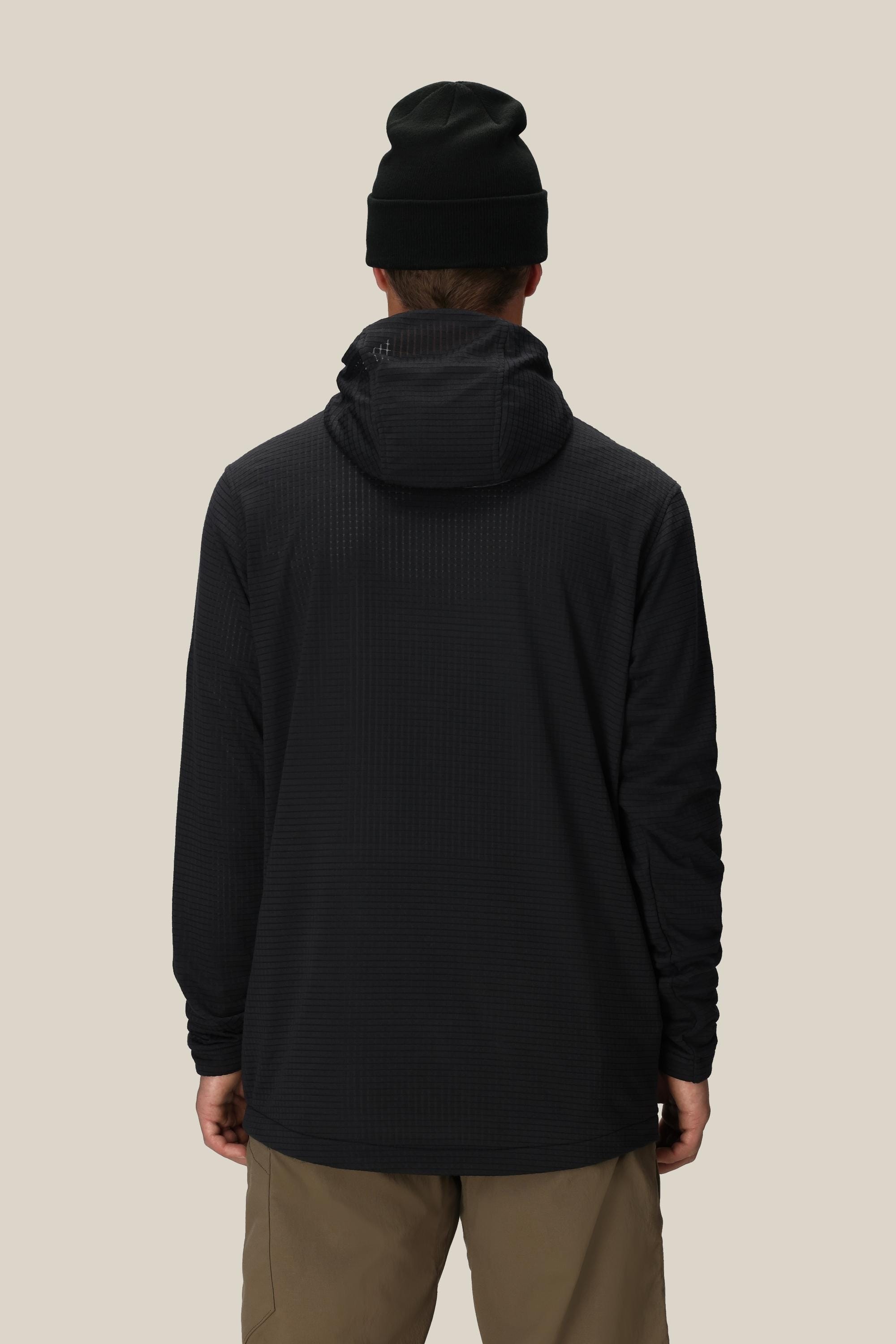 A person wearing a black beanie, beige pants, and the 686 Mens Mission Grid Fleece Hoody by 686 is shown from the back against a plain light beige background.