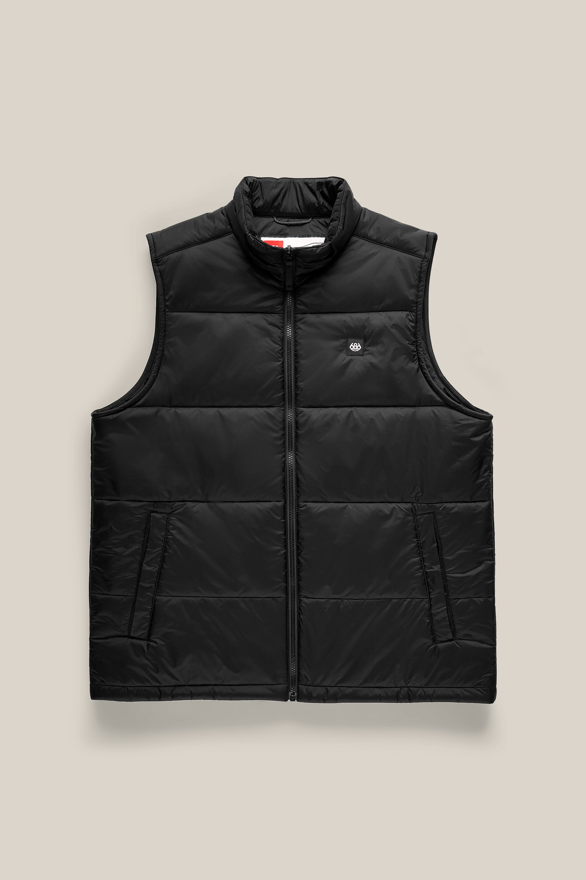 686 Men’s Rodeo™ Puffer Insulated Vest by 686, featuring a black nylon construction with a front zipper, sleeveless design, and a small white 686 logo on the left chest, displayed on a beige background.
