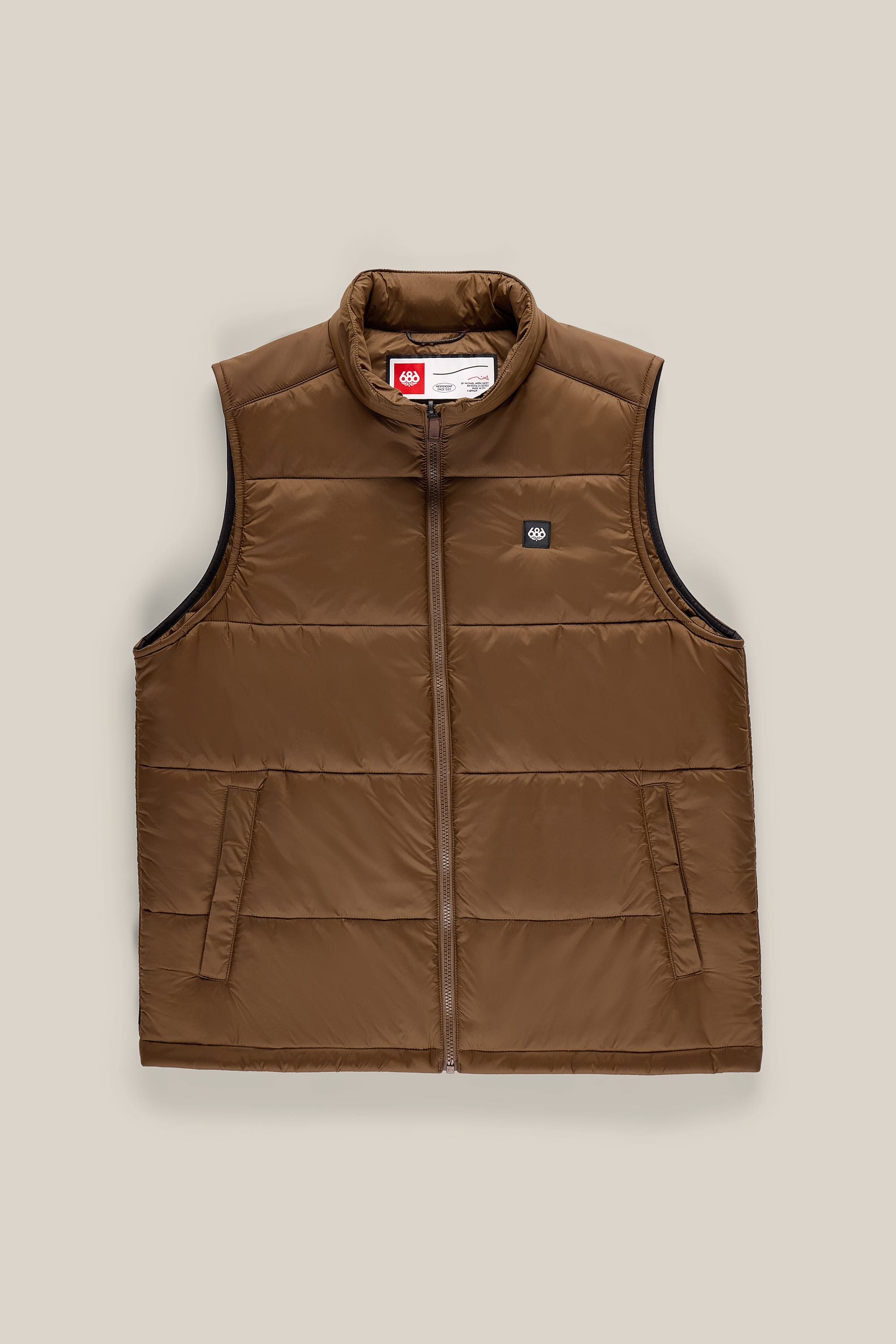 686 Men’s Rodeo™ Puffer Insulated Vest by 686, featuring a brown woven design with a front zipper, two side pockets, and a small logo patch on the left chest. This men’s vest is displayed laid flat on a neutral beige background.