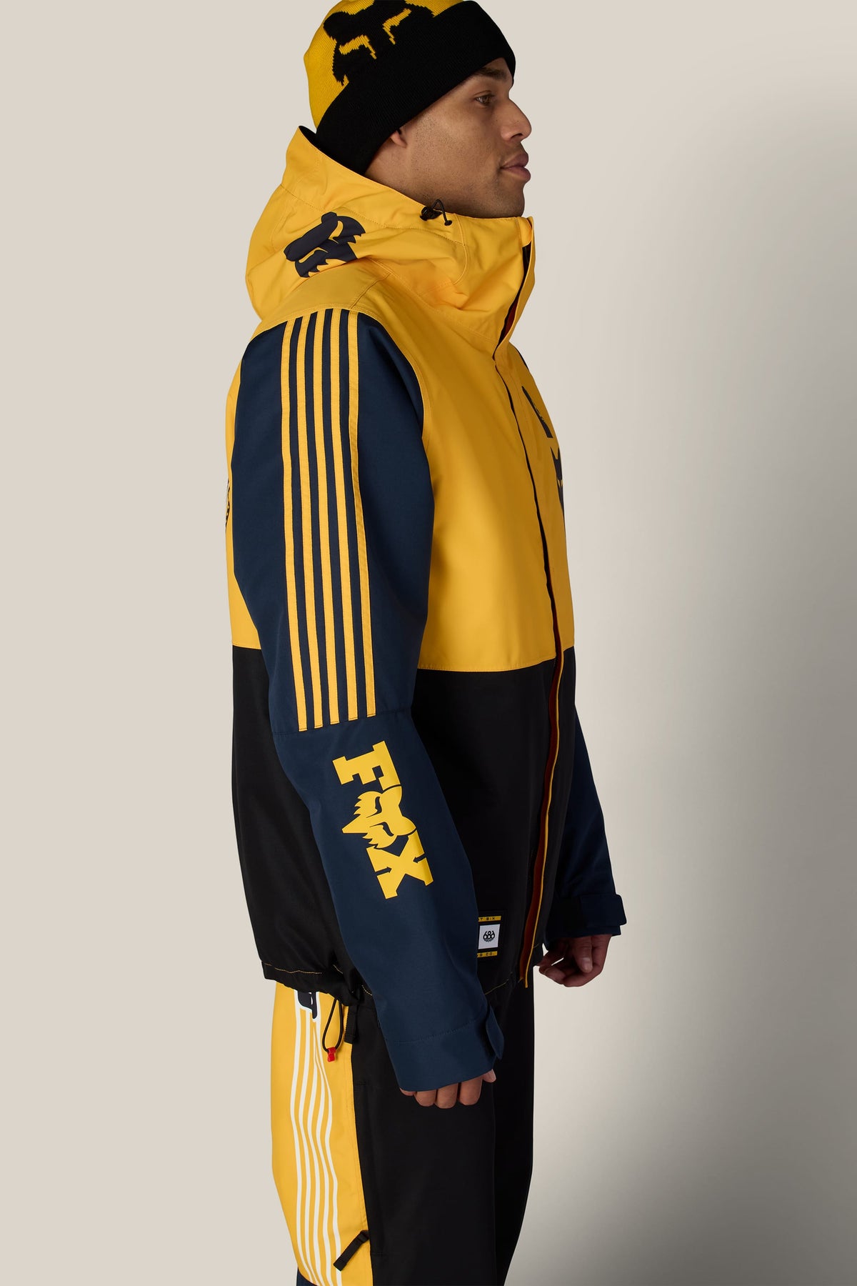 A person wearing a 686 Men’s Fox Racing Spec Insulated Jacket with a matching beanie and pants.
