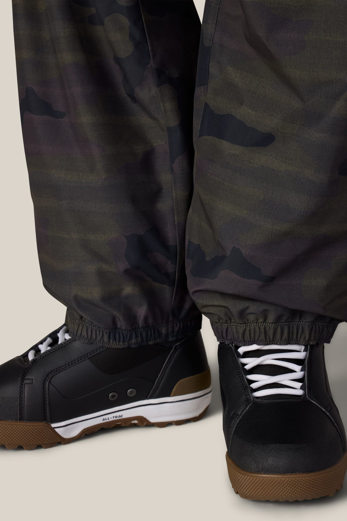 Close-up of a person wearing 686 Men’s Metallica One Shell Pant over black low-top sneakers with white laces and gum rubber soles.