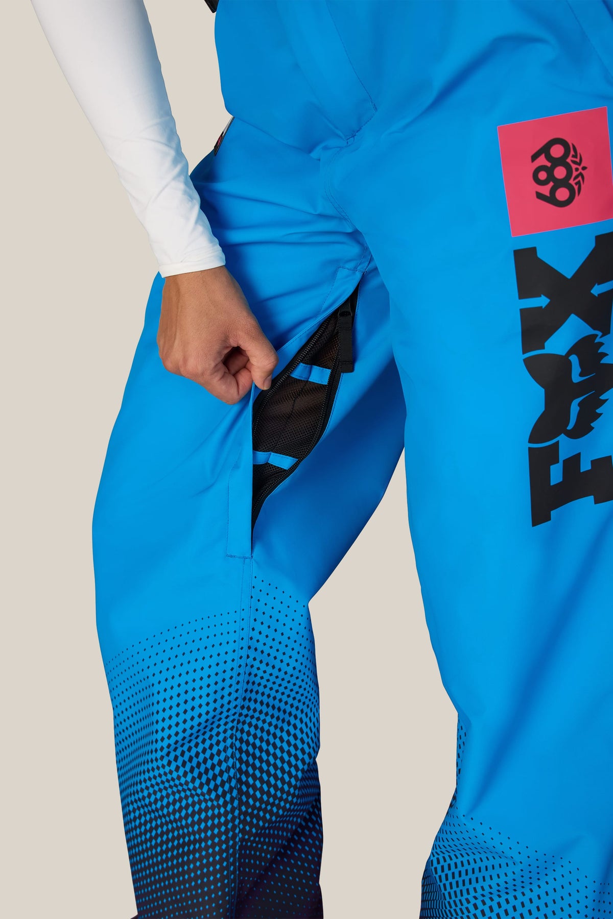 A close-up of a person unzipping the mesh-lined thigh vent on bright blue 686 Women’s Fox Racing 97 Shell Pant.