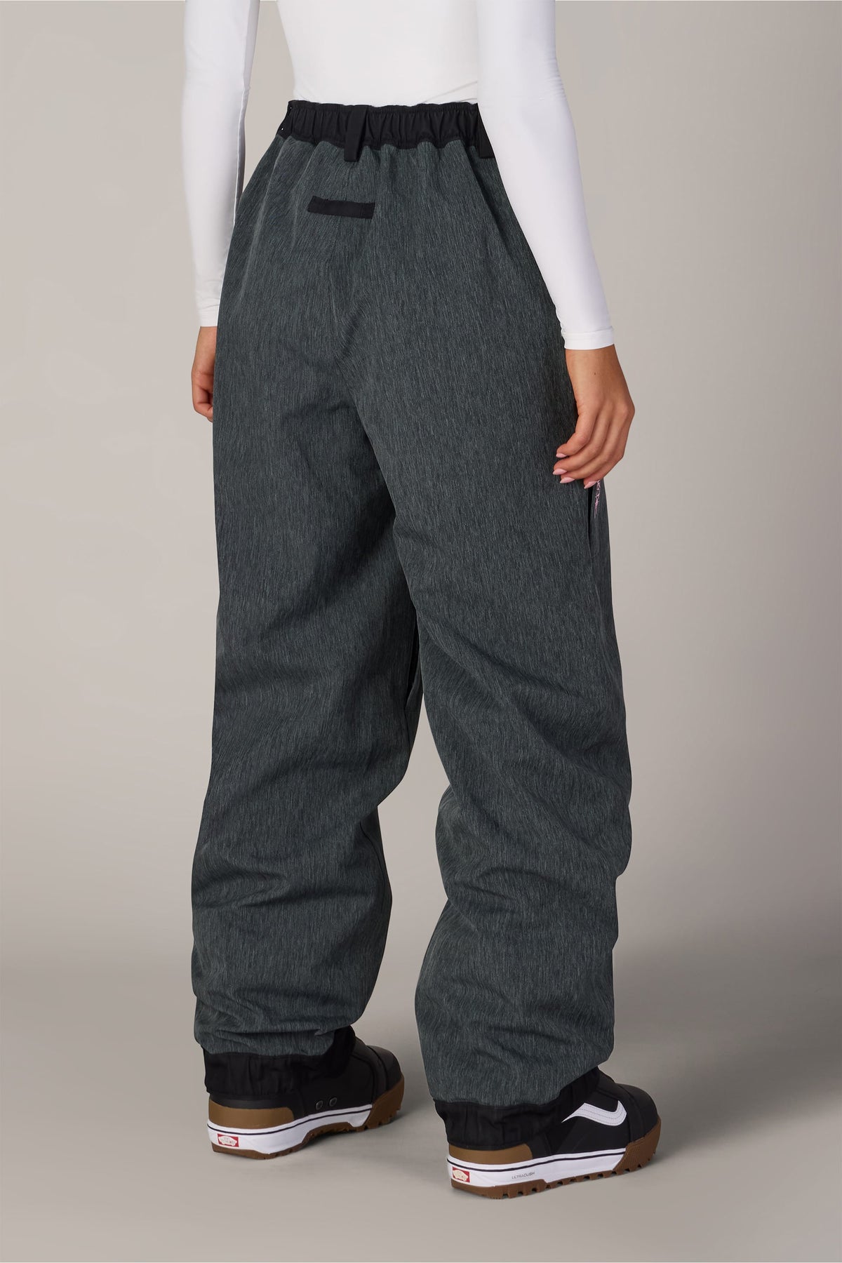 Back view of 686 Women’s Metallica Burning Skull Shell Pant in charcoal gray, featuring a black waistband and worn over black snow boots.