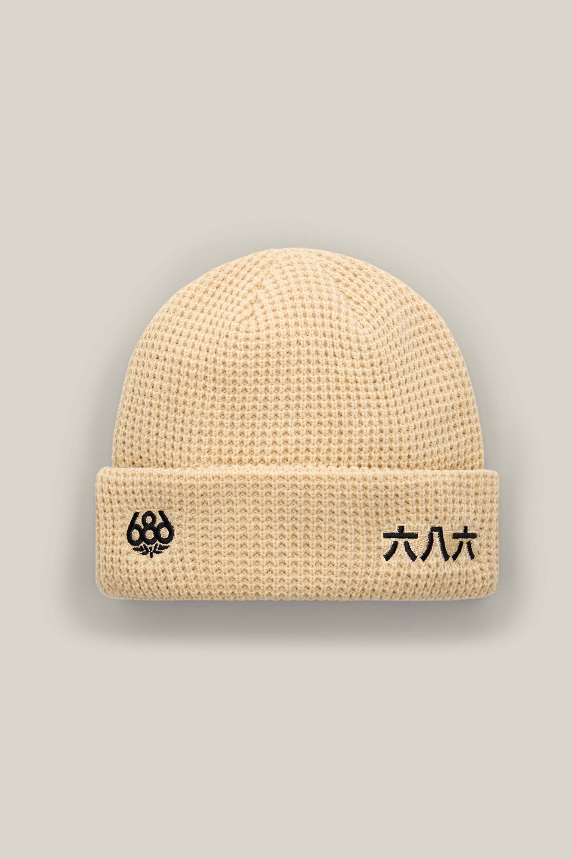 The 686 Kanji Beanie is a beige acrylic knit beanie with a folded brim, featuring the 686 logo and black Chinese characters on the front. The background is a plain light beige.