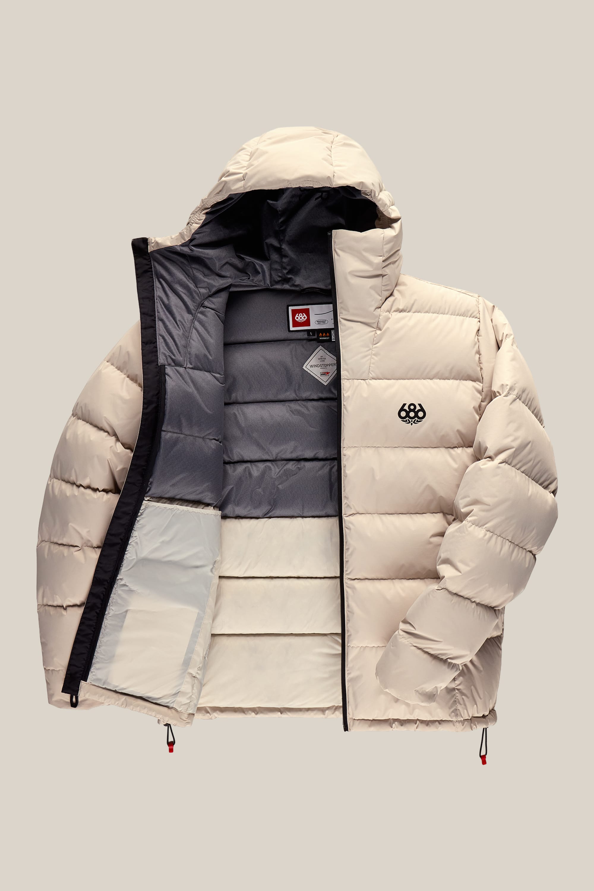 A cream-colored 686 Men’s WINDSTOPPER® Pyro™ Down Puffer Jacket by GORE-TEX® LABS features a hood, a partially unzipped front that reveals a dark gray interior lining with inner pockets, and a small black 686 logo on the left chest. Crafted from polyester, this men’s puffer showcases both style and functionality.