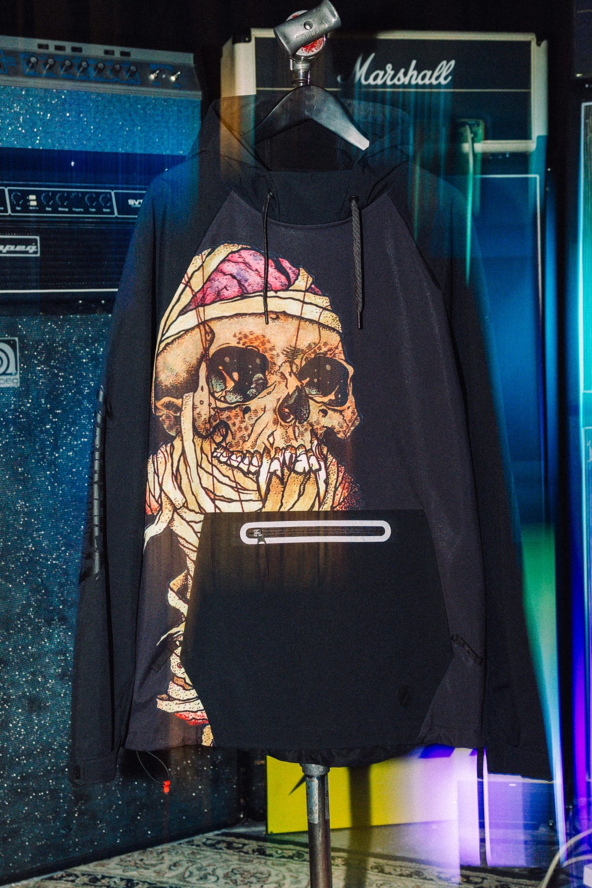 Black 686 Men’s Metallica Waterproof Hoody featuring a large graphic of a skull wrapped in bandages on the front and a zippered kangaroo pocket.