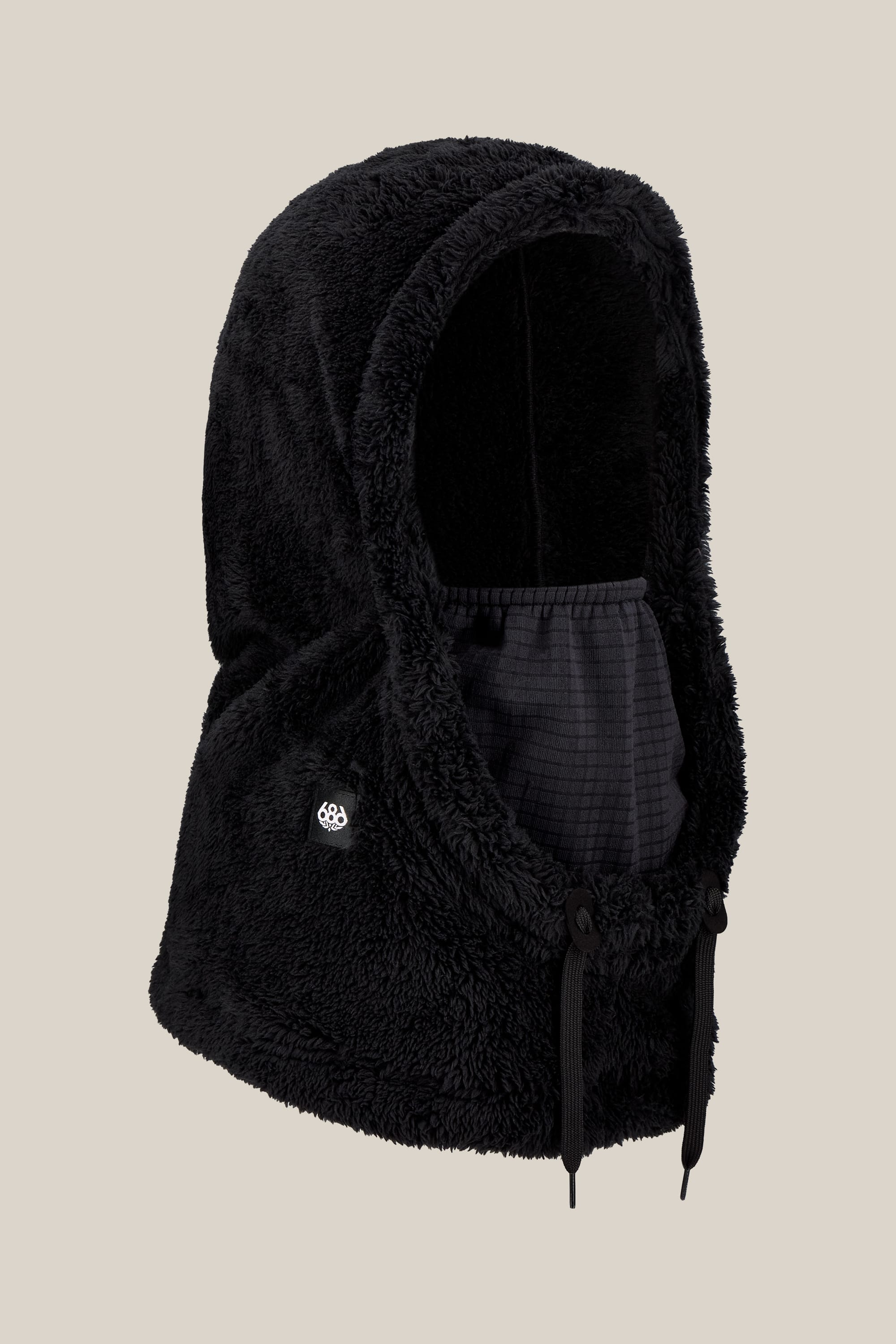 The 686 Tarmac Sherpa Hood by 686 is a black, fuzzy polyester knit hood featuring a face covering and adjustable drawstrings, shown against a plain beige background.