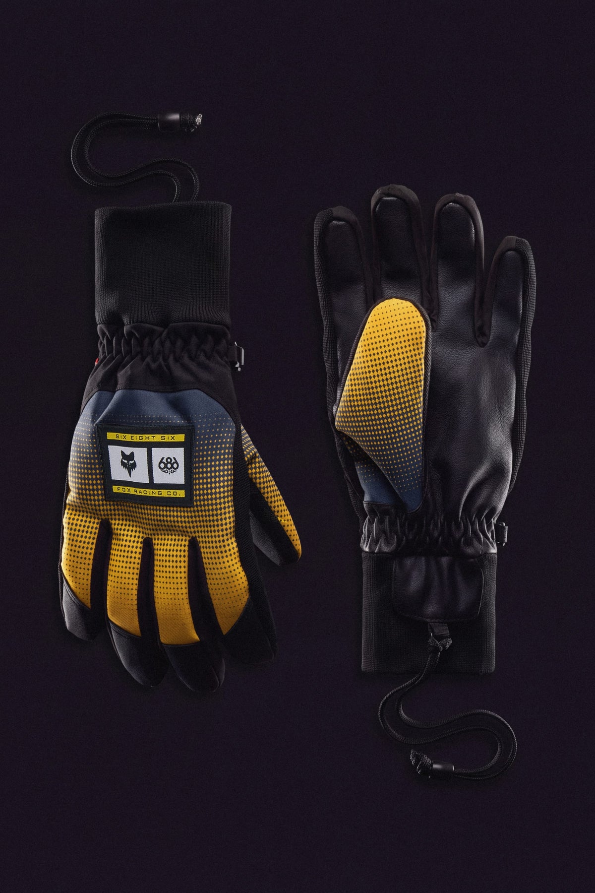 Two pairs of 686 Men’s Crush Insulated Glove in black, yellow, and blue with textured palms, cuffs, and wrist straps. One glove displays a logo label. Solid black background.