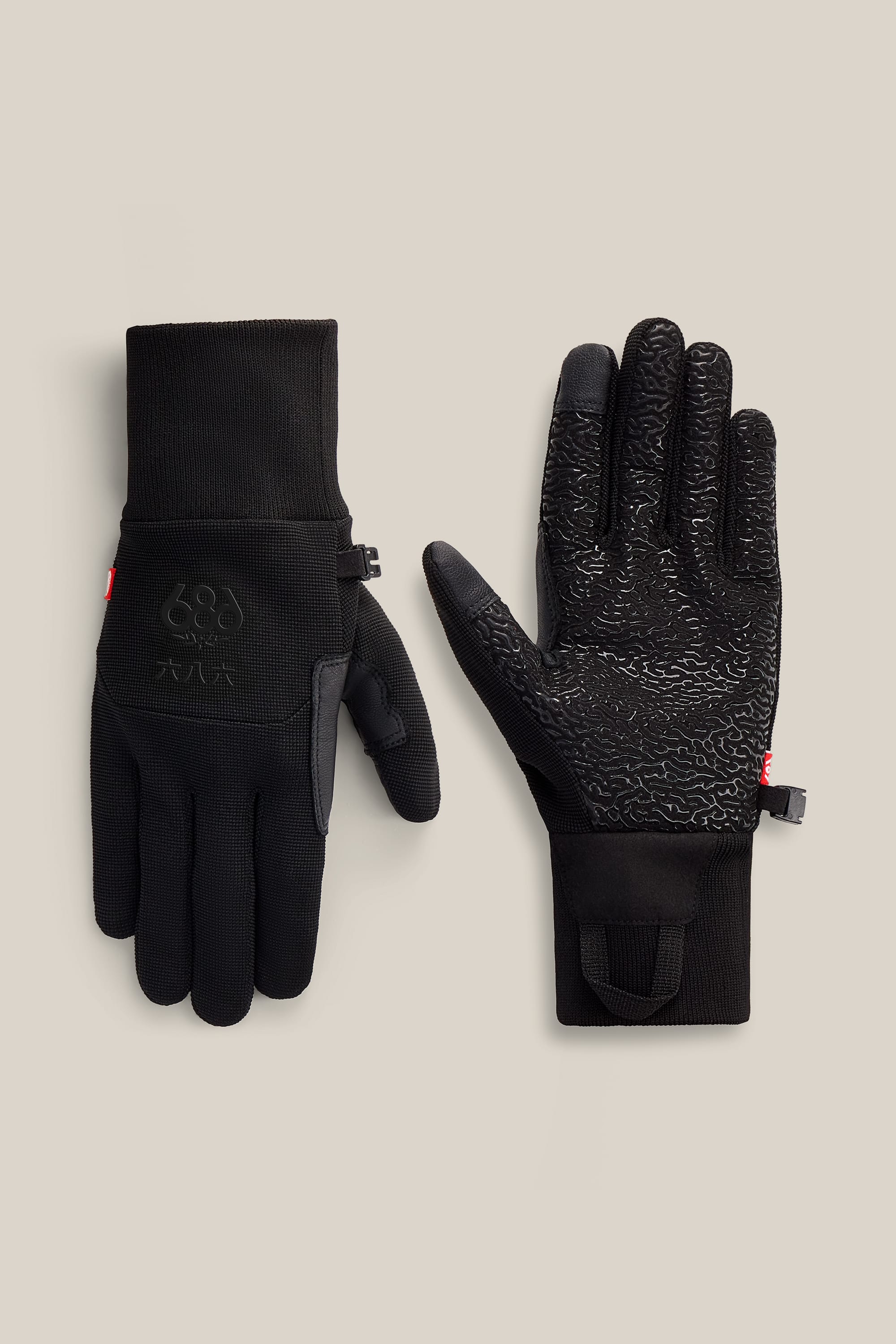 A pair of 686 Men’s Hold Up Pipe Gloves is shown, one palm up and one palm down. The palm side features a textured grip, and the gloves include a small clip to keep them together.