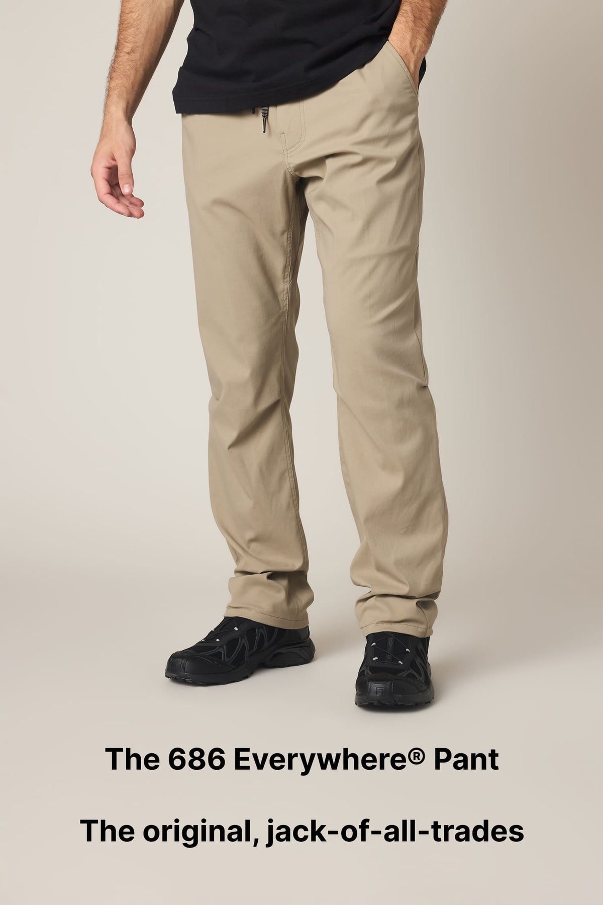 A person models beige pants and black shoes against a neutral background. Text at the bottom reads: The 686 Everywhere® Pant. The original, jack-of-all-trades..