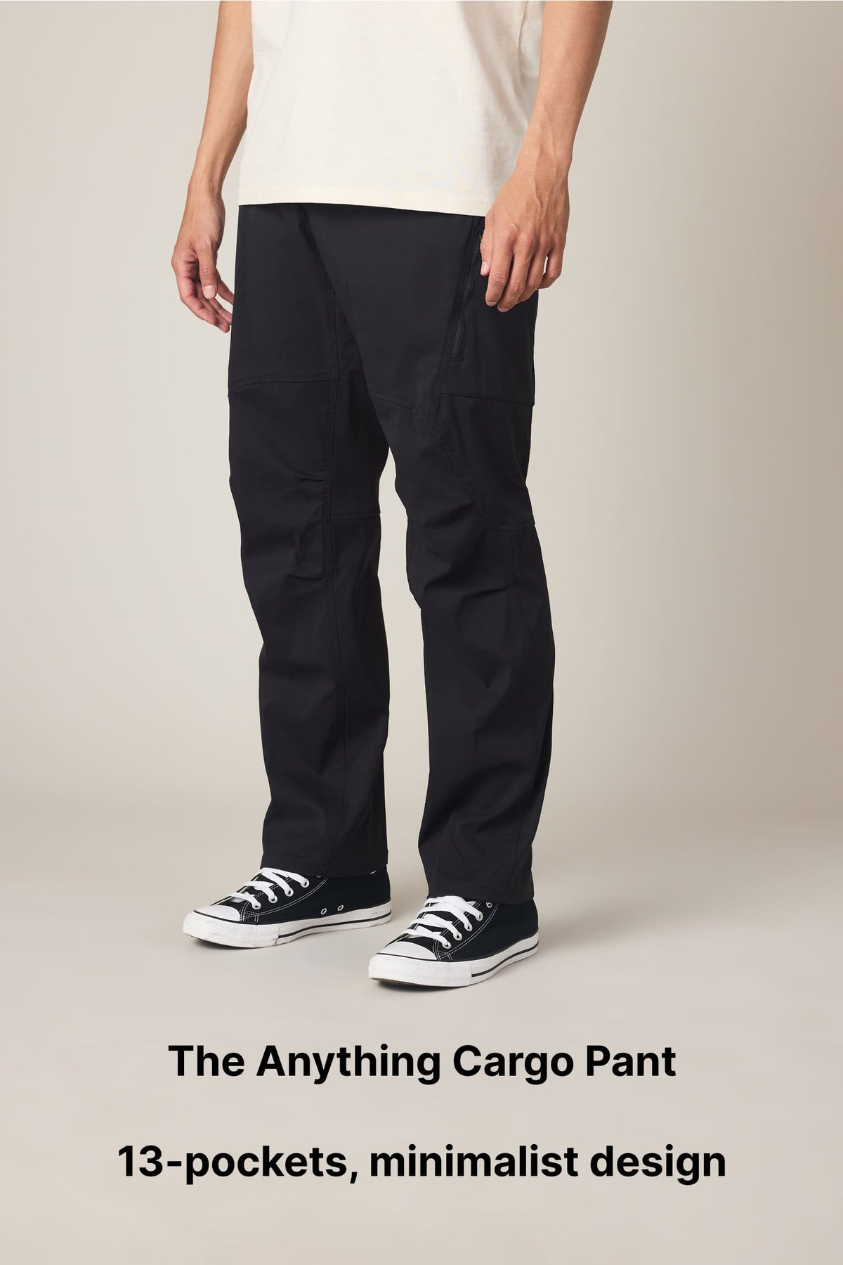 A person wearing black cargo pants and black sneakers stands against a plain background. Text below reads: The Anything Cargo Pant. 13-pockets, minimalist design..