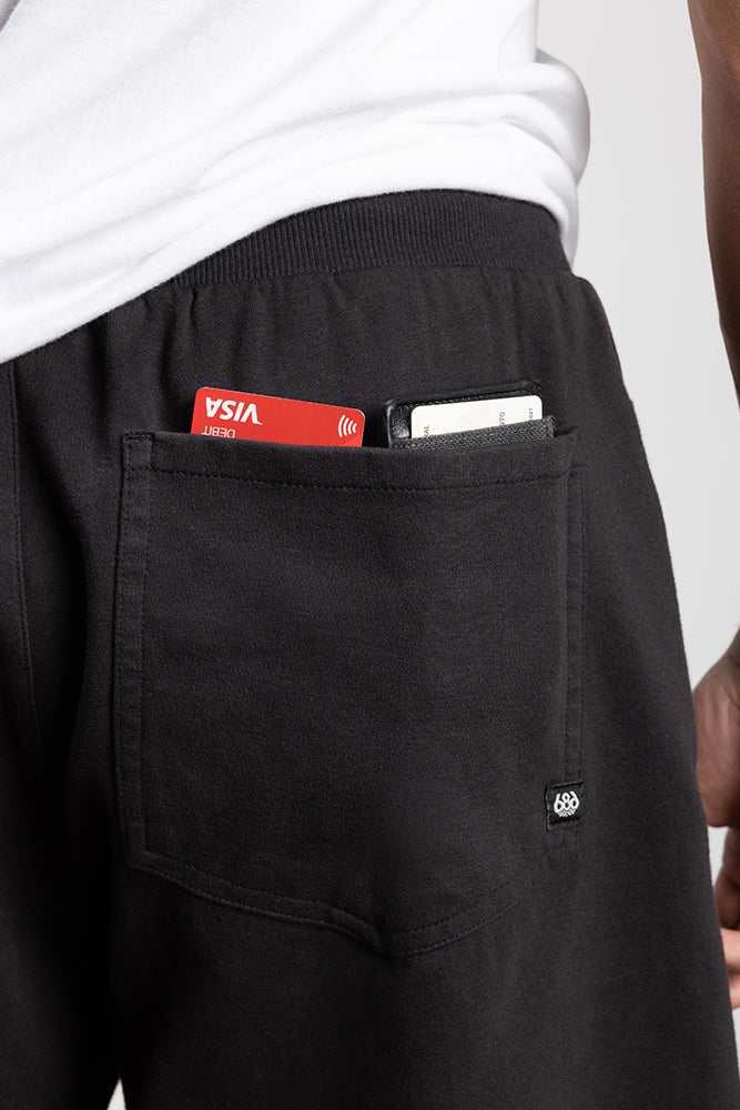 A person wearing 686 Mens Everywhere Double Knit Shorts with a back pocket holding a red Visa debit card and smartphone, visible against a white shirt background.