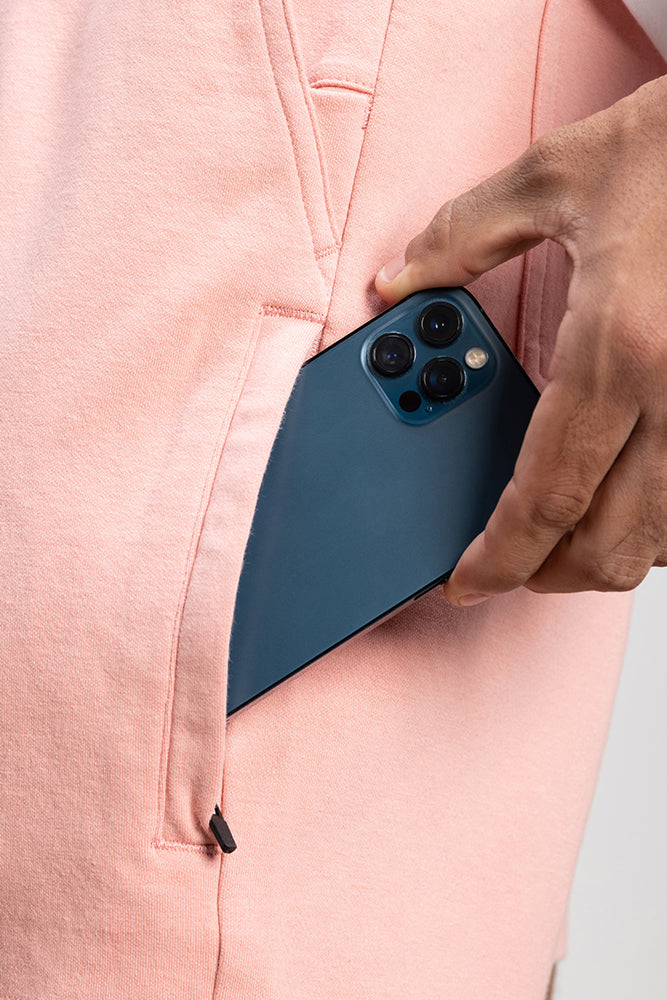 A hand places a blue smartphone with three cameras into the pocket of 686 Mens Everywhere Double Knit Short by 686.